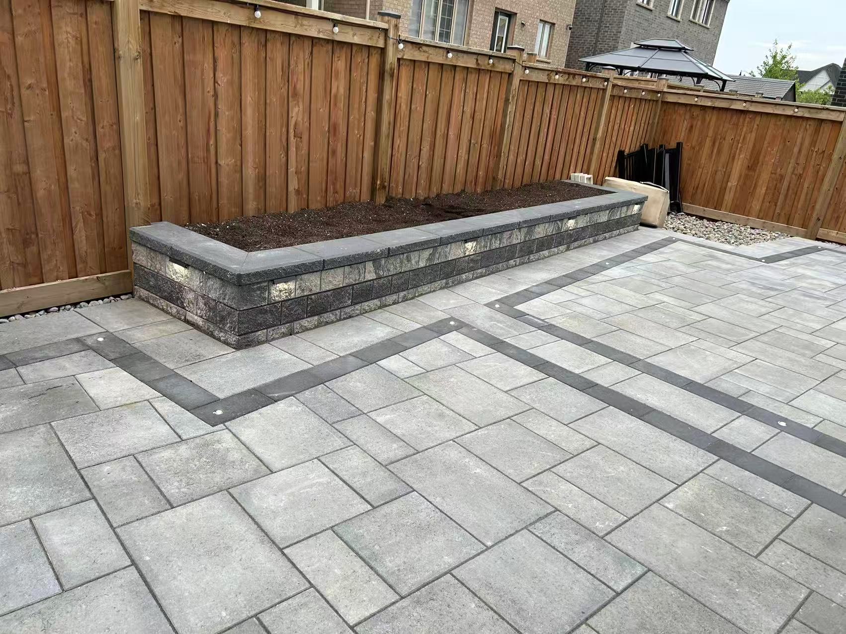 Backyard patio with raised garden bed retaining wall and interlock accent strips